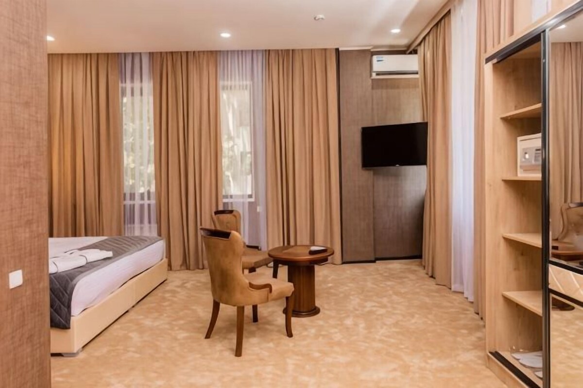 Una habitación de hotel con cama, una silla, una mesita, televisión y armario.