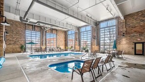 A spacious indoor pool area with multiple seating arrangements and large windows providing natural light.