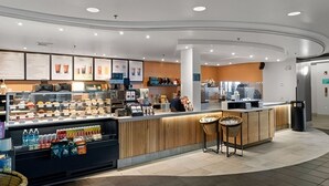 Un café moderne avec un comptoir en bois, un espace salon et une grande variété de boissons.