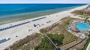 Un complexe hôtelier de bord de mer doté d’une piscine, de parasols et d’une plage.