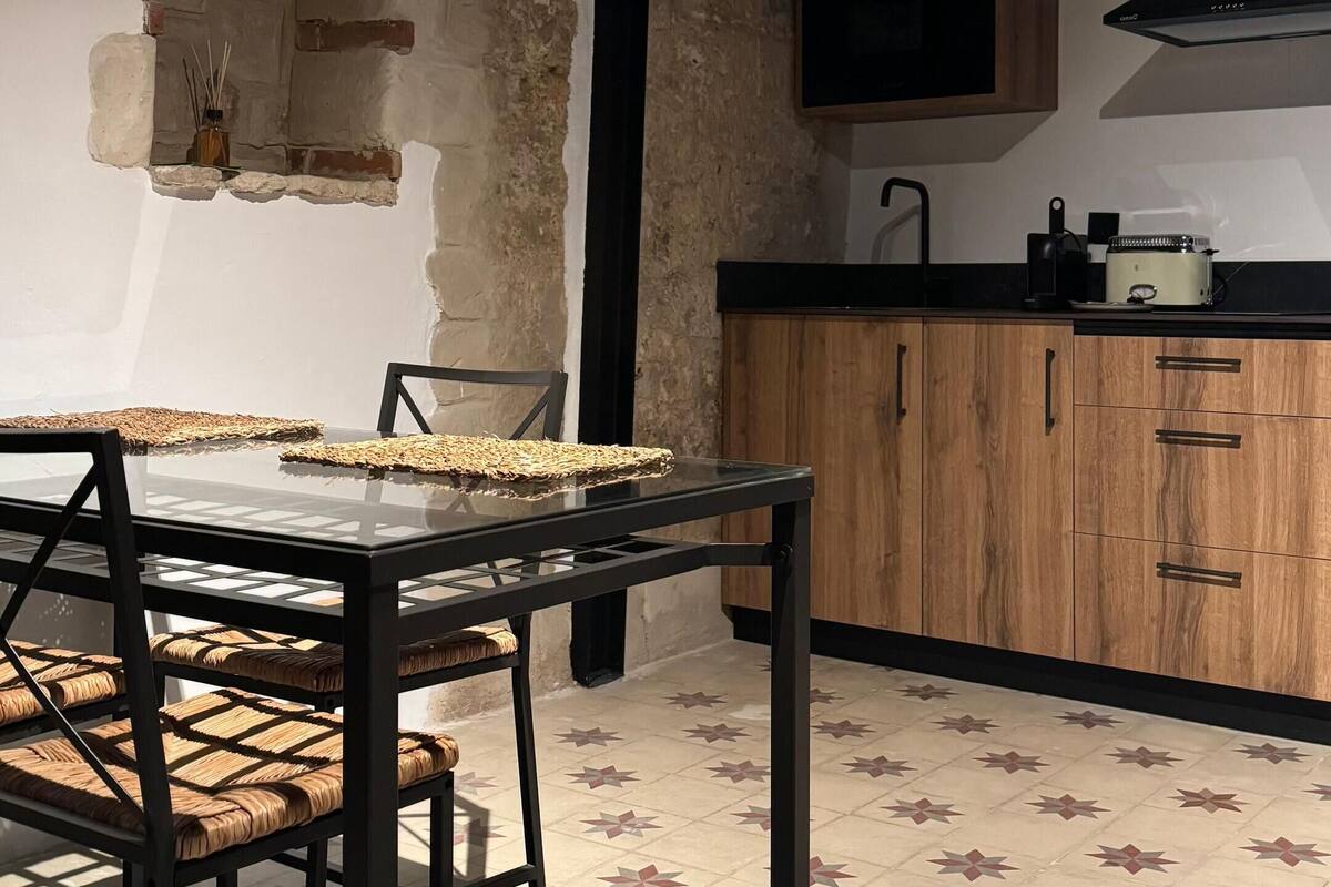 Une cuisine avec un mur en pierre rustique, un meuble en bois et un sol carrelé orné de motifs en étoile.