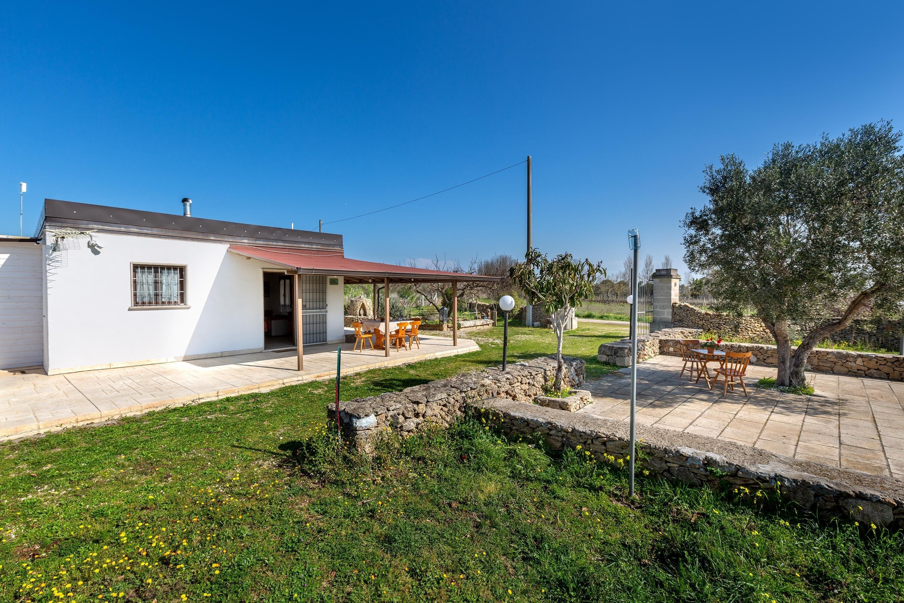 A house with a patio, a stone wall, and a tree.