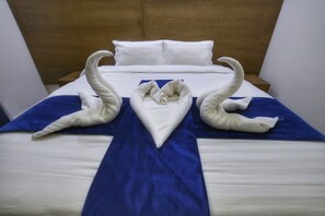 A hotel room with a neatly made bed, a wooden headboard, and a blue bedspread. - Zouk AlKhayal Hotel  (Makkah)