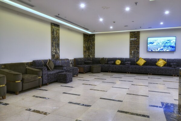 A modern lobby with a sectional sofa, armchairs, and a flat-screen TV on the wall. - Zouk AlKhayal Hotel  (Makkah)