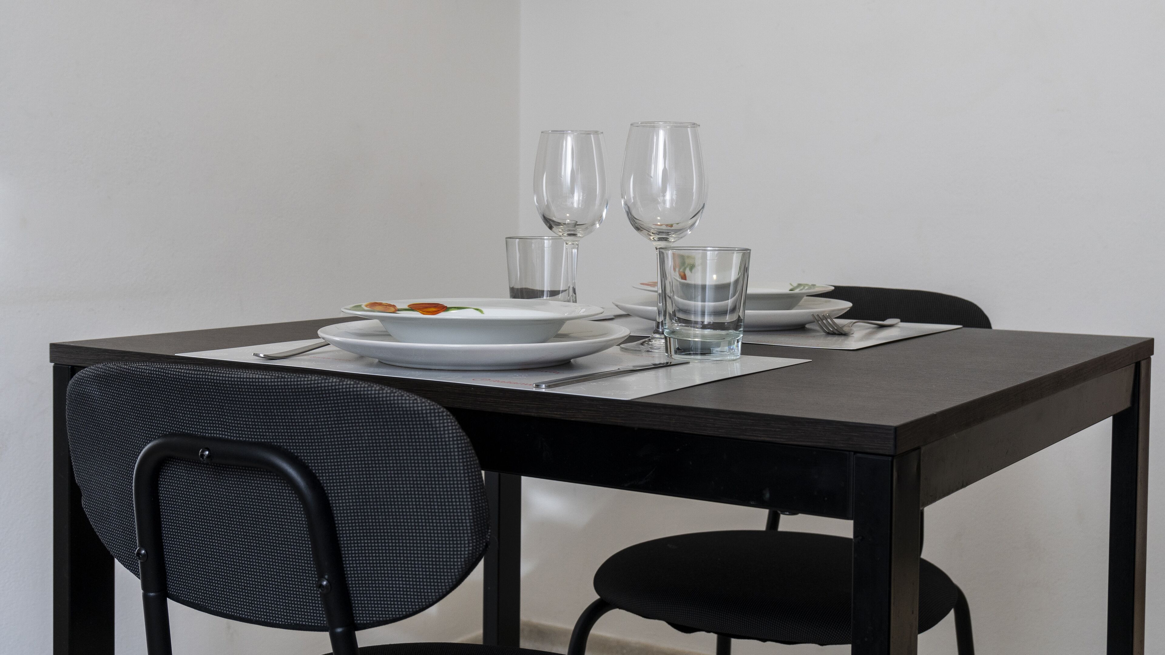 Een eettafel gedekt met borden, glazen en bestek.