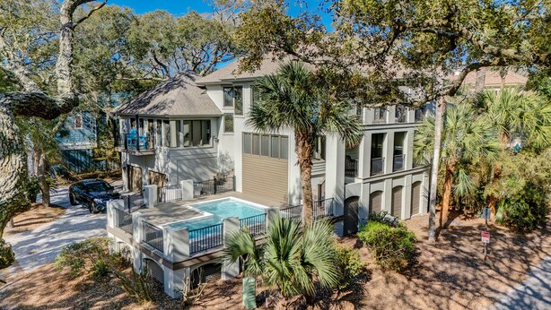 A two-story house with a swimming pool, surrounded by trees and a well-maintained garden.