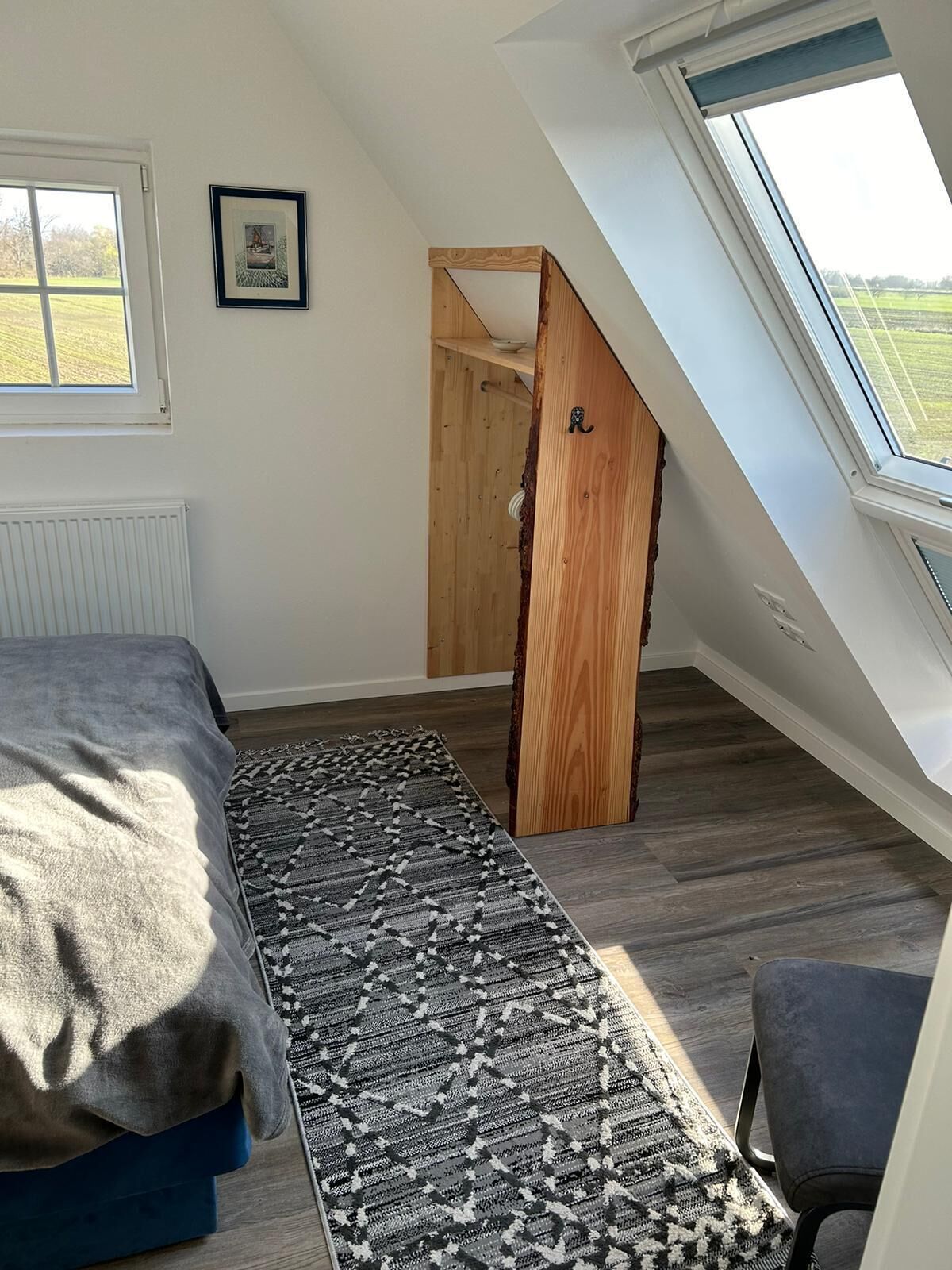 Un dormitorio con techo inclinado, una cama, un tapete y una ventana.