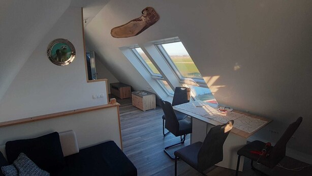 A loft bedroom with a sloped ceiling, skylight, and a view of the outdoors. - Ferienwohnung "weit Blick" (Dornum)
