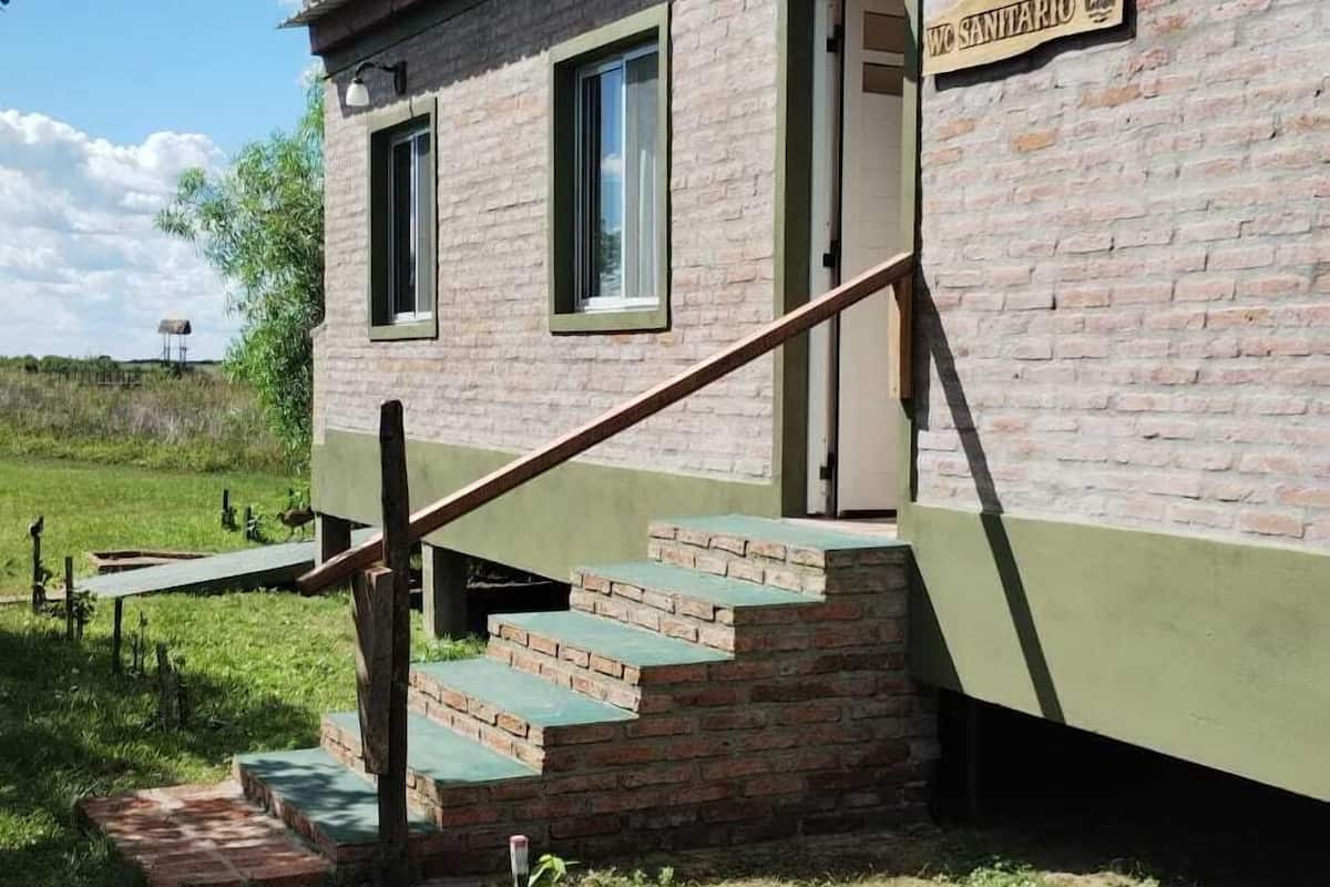 A building with a sign reading "WC SANTARIO" and a staircase leading to the entrance.