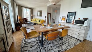 A dining area with a wooden table, chairs, and a patterned rug. - L'appartement Poulbot (Paris)