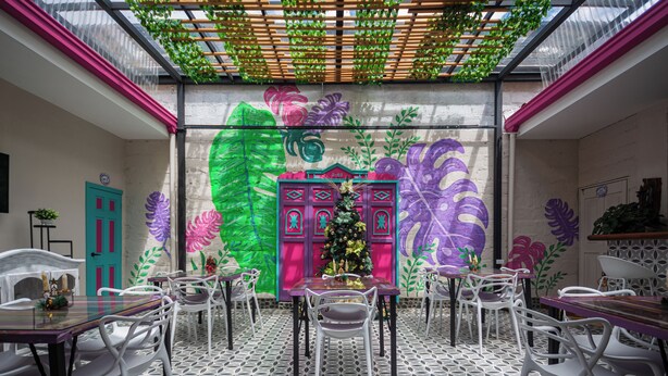 A dining area with a patterned floor, white chairs, and a table with a Christmas tree centerpiece. - CASA HOTEL LAS HORTENSIAS (Jardin)