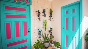 A turquoise door with pink accents, a tiled floor, and potted plants on the wall. - CASA HOTEL LAS HORTENSIAS (Jardin)