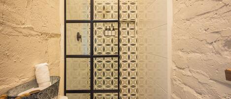 A bathroom with a white bathtub, a glass shower enclosure, and a patterned wall.