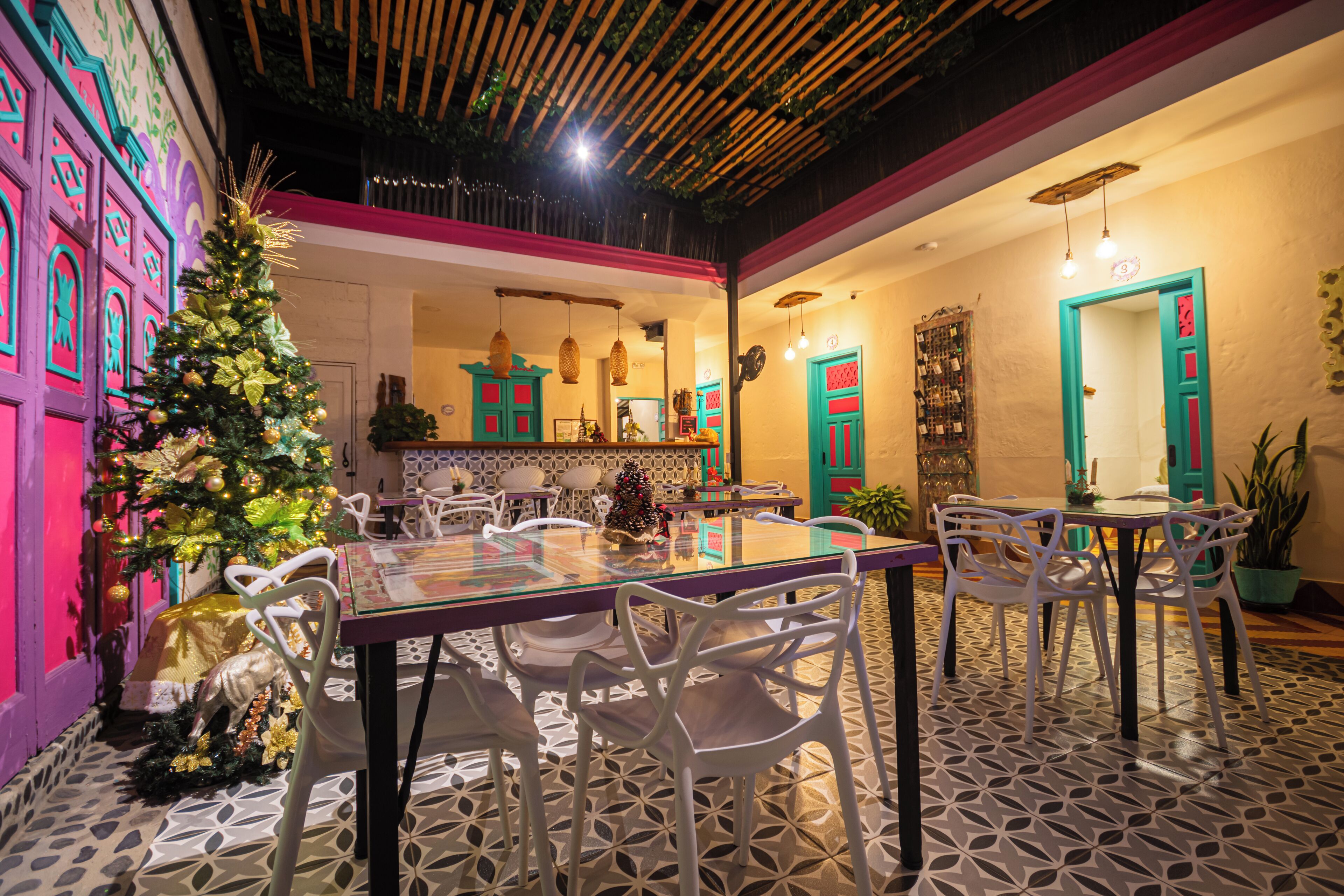 Comedor con árbol de Navidad, sillas blancas y piso estampado.