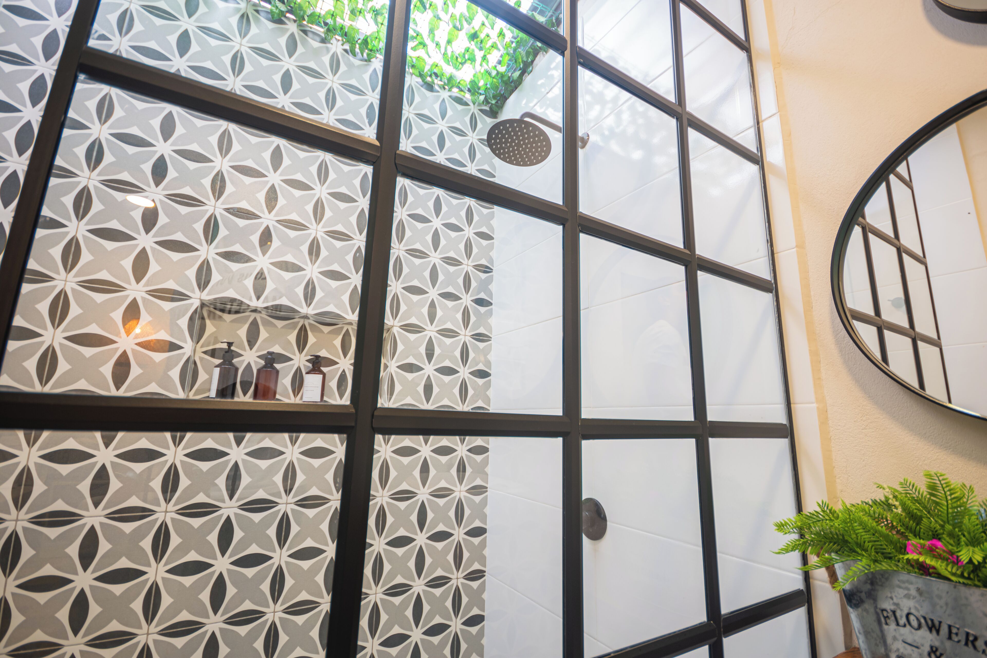 A bathroom with geometric patterned walls, a shower area, and a potted plant with flowers.