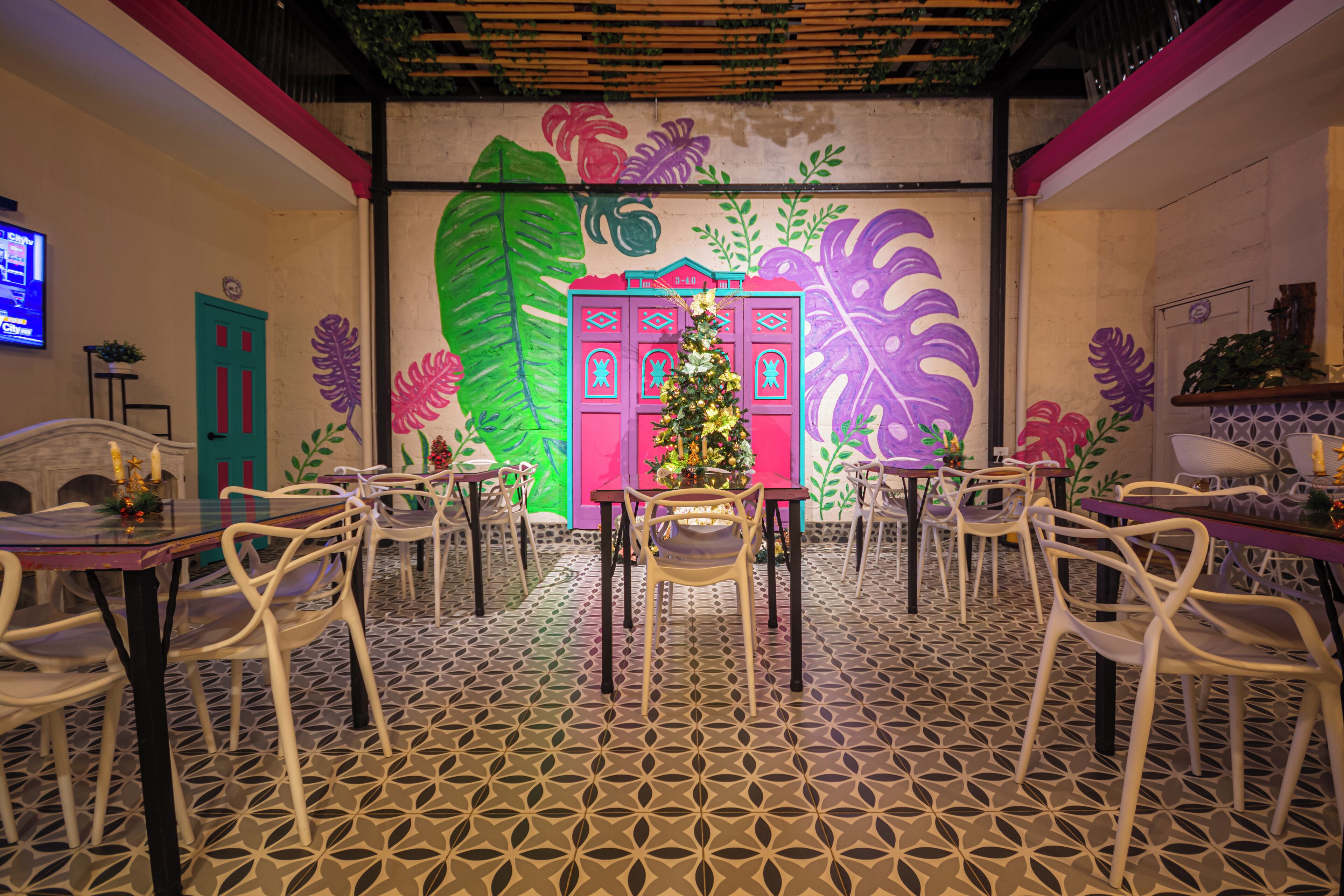 A dining area with a patterned floor, white chairs, and a central table with a Christmas tree.