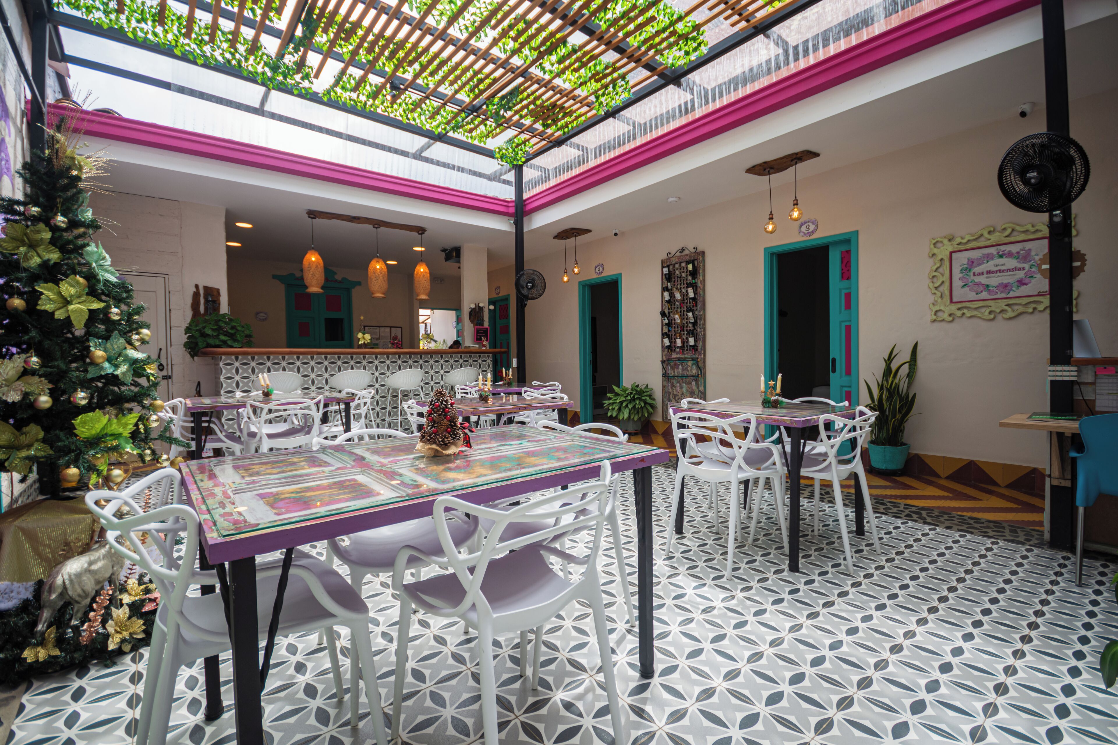 Un restaurante con techo alto, plantas verdes y un árbol de Navidad.
