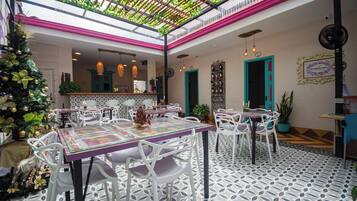 Un ristorante con soffitto alto, piante verdi e un albero di Natale.