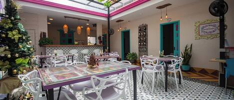Un restaurante con techo alto, plantas verdes y un árbol de Navidad.