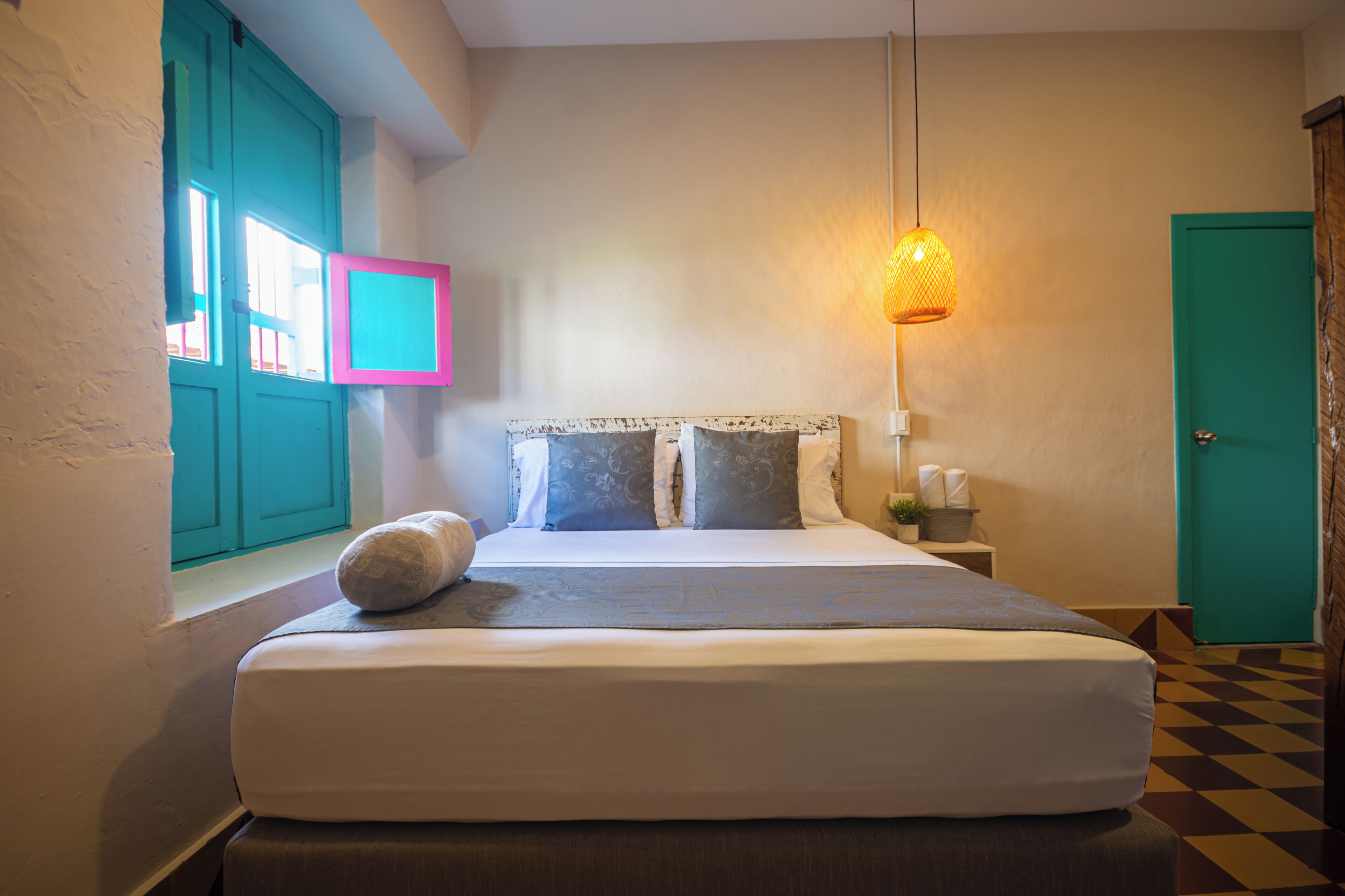 A bedroom with a bed, a nightstand, a lamp, and a window with a view.