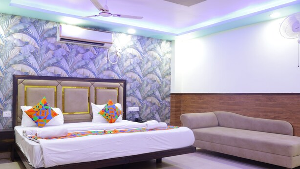 A hotel room with a bed, a sofa, an air conditioning unit, and a ceiling fan. - TRPOTEL SUBMANGAL (Gwalior)