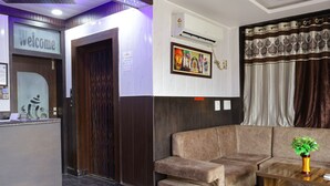 A reception area with a 'Welcome' sign, a reception desk, a sofa, and a coffee table with a plant. - TRPOTEL SUBMANGAL (Gwalior)