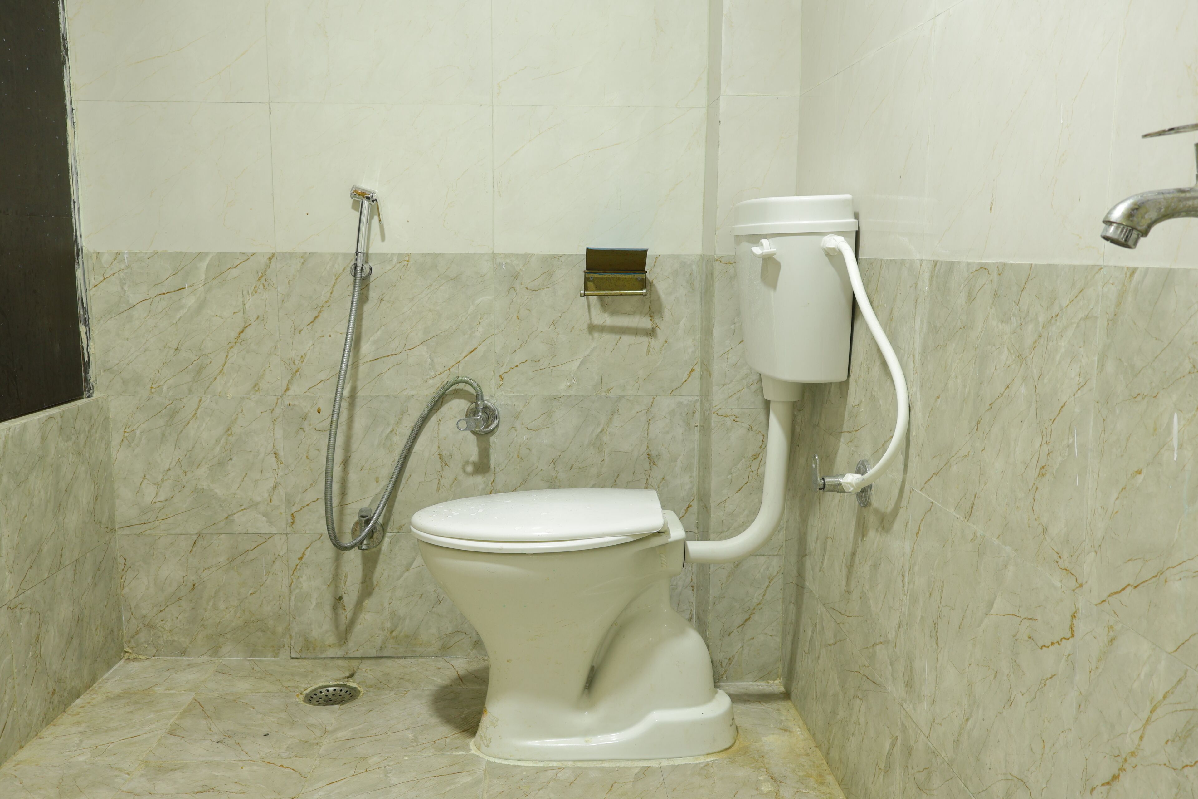 Une salle de bain équipée de toilettes, d’une douche et d’un porte-rouleau de papier toilette fixé au mur.
