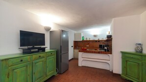 Eine kompakte Küche mit Fernseher, Kühlschrank, Mikrowelle und einer kleinen Essecke.