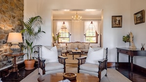 A cozy living room with a stone wall, two armchairs, a sofa, a coffee table, and a chandelier.