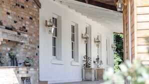 A white building with brick walls, large windows, and decorative lanterns.