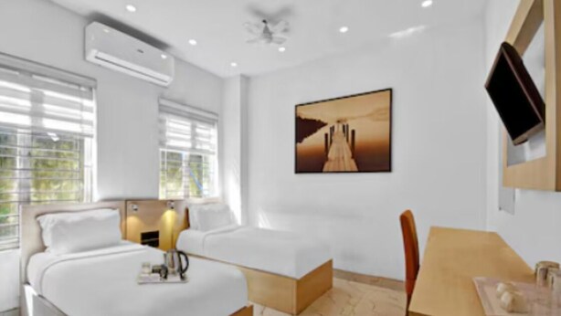 A modern hotel room with a large bed, a desk, and a chair. There is a painting on the wall and an air conditioning unit on the ceiling. - Hotel Silver Stay By GRB (New Delhi)