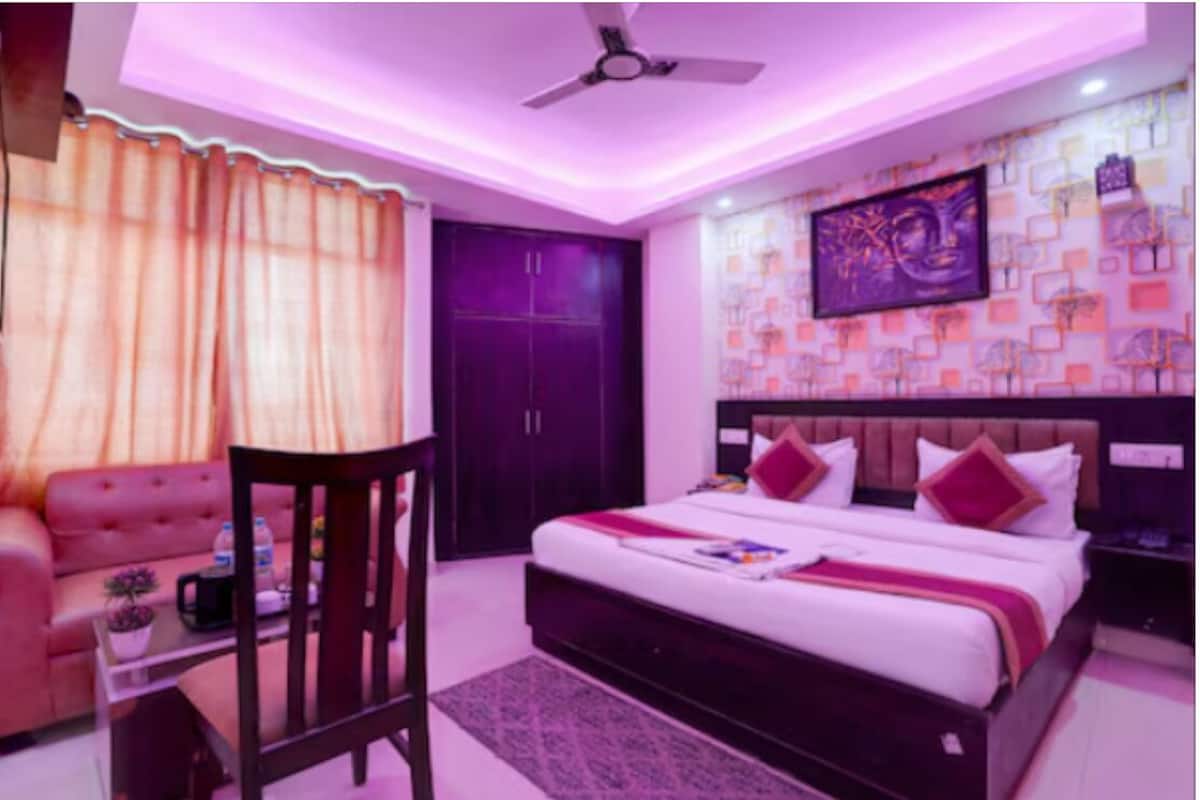 A bedroom with a bed, a chair, a desk, a ceiling fan, and a wardrobe.