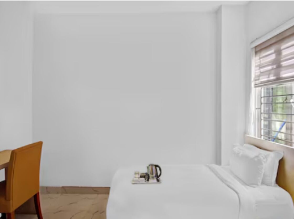A room with a bed, a chair, and a window with blinds.