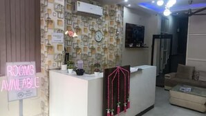 A reception area with a 'Rooms Available' sign, a patterned wall, a clock, and a reception desk with a pink decorative element. - Hotel Silver Stay By GRB (New Delhi)