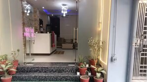 A hotel entrance with a reception desk, neon sign, and potted plants. - Hotel Silver Stay By GRB (New Delhi)