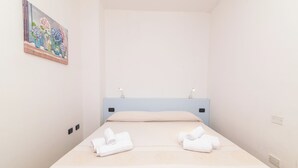Una habitación de hotel con una cama, dos mesitas de noche, un cuadro en la pared y toallas sobre la cama.