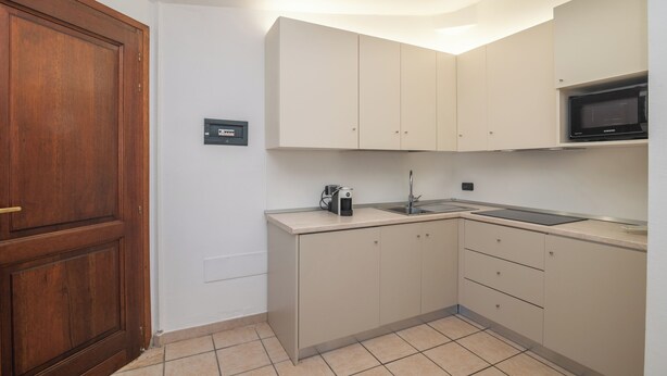 Una cocina compacta con microondas, lavamanos y armarios.