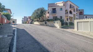 Una calle residencial con casas, un camino asfaltado y un cielo azul despejado.