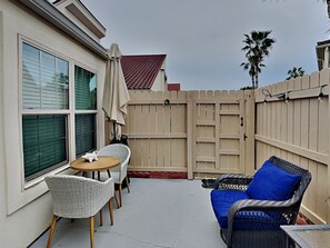 A patio with wicker furniture, a small round table, and a blue cushion.