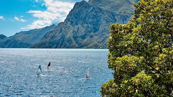 A lake with sailboats, surrounded by mountains and dense foliage.