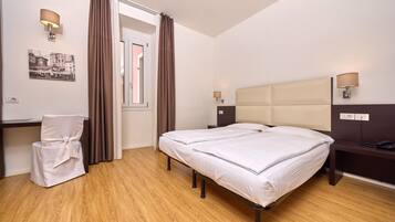 Een hotelkamer met een bed, een bureau, een stoel en een raam met gordijnen.