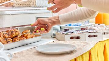 Ein reichhaltiges Buffet mit verschiedenen Speisen, darunter Gebäck und einem Tablett Croissants.