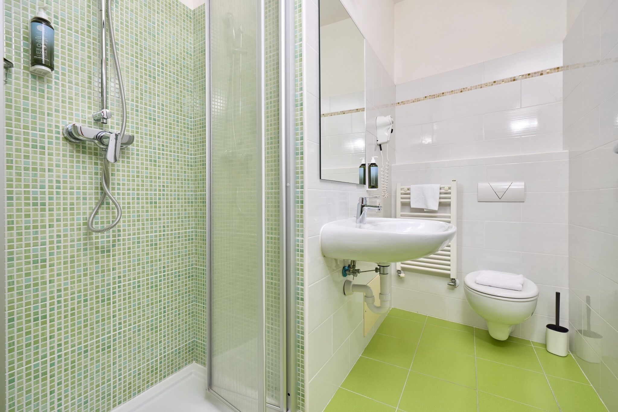 A bathroom with a shower, sink, toilet, and a mirror.