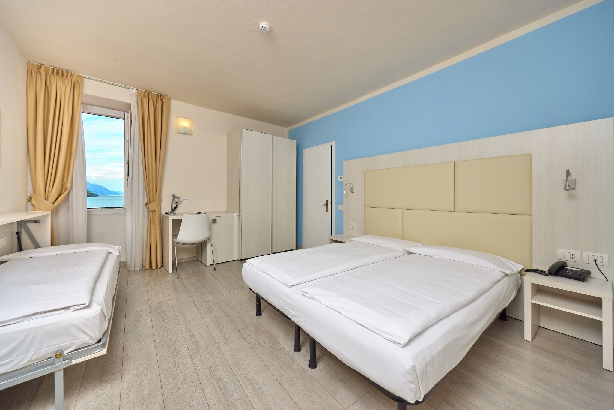Une chambre d’hôtel avec deux lits, un bureau, une chaise et une vue sur la mer.