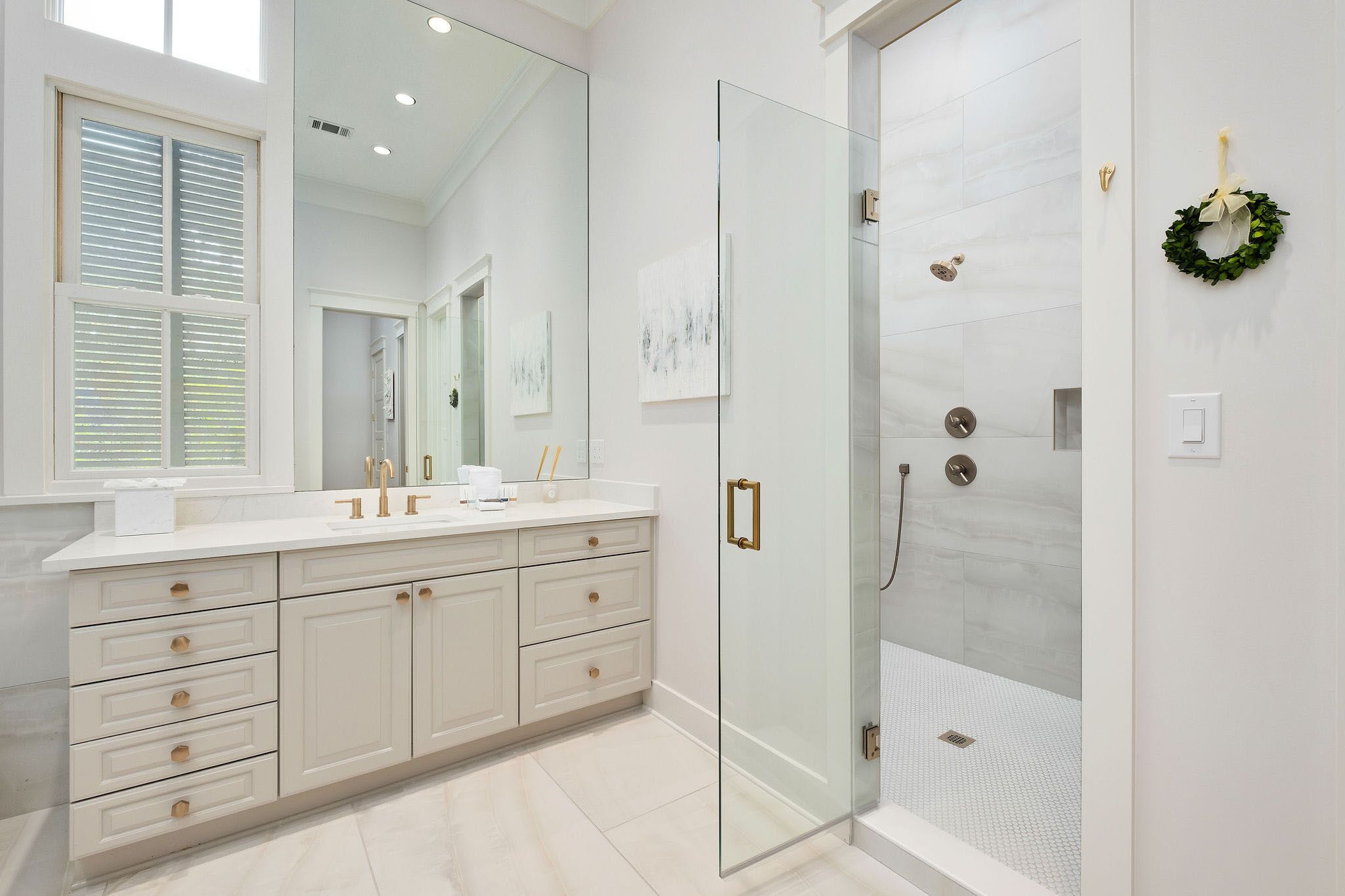 Une salle de bain moderne dotée d’une douche à parois de verre, d’un grand miroir et d’un meuble-lavabo avec plusieurs tiroirs.