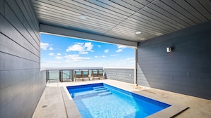 Una piscina interior moderna con vistas despejadas al cielo y una zona de estar con sillas.