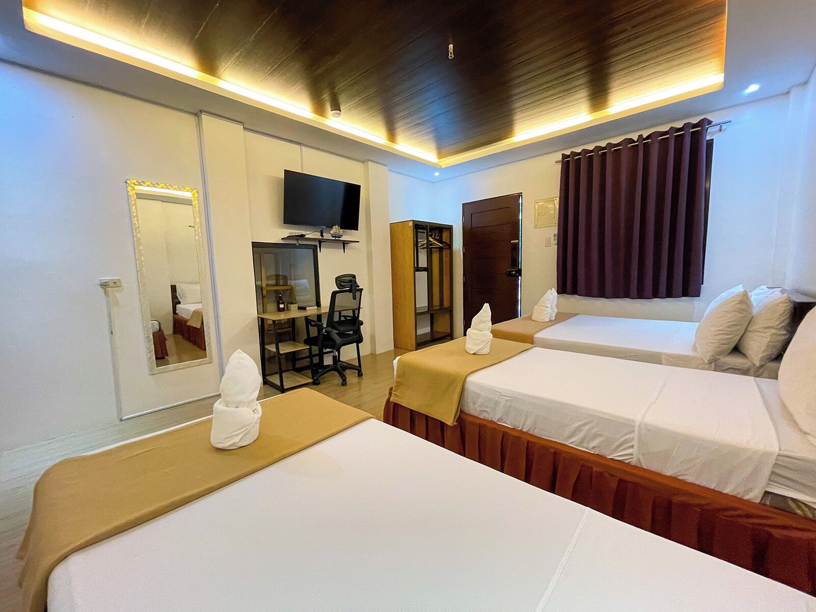 A hotel room with two beds, a desk, a chair, a television, and a mirror.