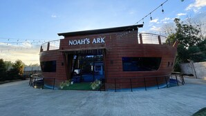 Un bâtiment en bois avec une enseigne indiquant « L’Arche de Noé » et une petite entrée.
