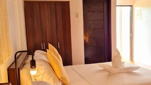 Une chambre d’hôtel avec deux lits, une armoire en bois et une porte.