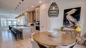 Una cucina moderna con isola centrale, mobili bianchi e illuminazione a sospensione.
